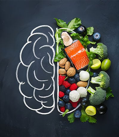 relación de párkinson y nutrición expresado en un cerebro divido en comida, con la mitad llena de comida saludable.